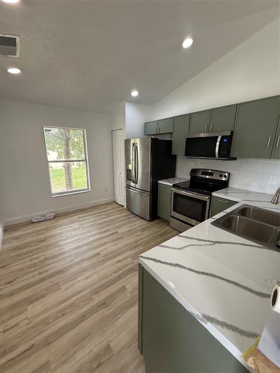 A kitchen features sage green cabinets, white marble-look countertops, and a stainless steel stove — 318 WALPOLE LOOP, DAVENPORT, FL