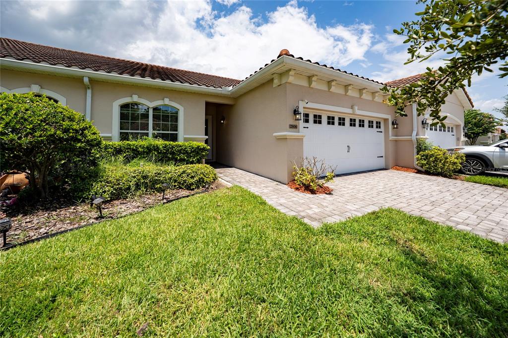 A single-story house with a beige stucco exterior, a tiled roof, and a paved driveway — 2806 PLYMOUTH PLACE, KISSIMMEE, FL