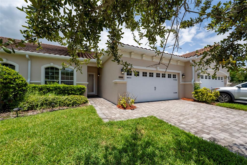 A single-story house with a white garage, paved driveway, and landscaped front yard — 2806 PLYMOUTH PLACE, KISSIMMEE, FL