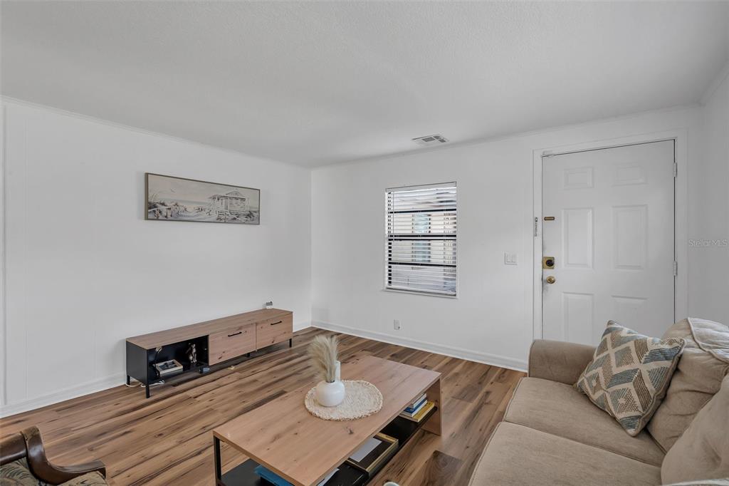 A living room features white walls, wood-look flooring, a sofa, a coffee table, and a console — 373 ERON WAY UNIT 47, WINTER GARDEN, FL