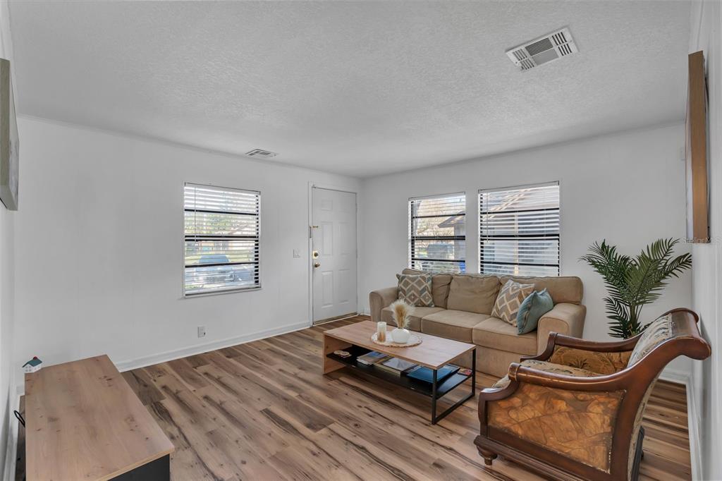 A living room features wood-look flooring, a beige sofa, a coffee table, and a chair — 373 ERON WAY UNIT 47, WINTER GARDEN, FL