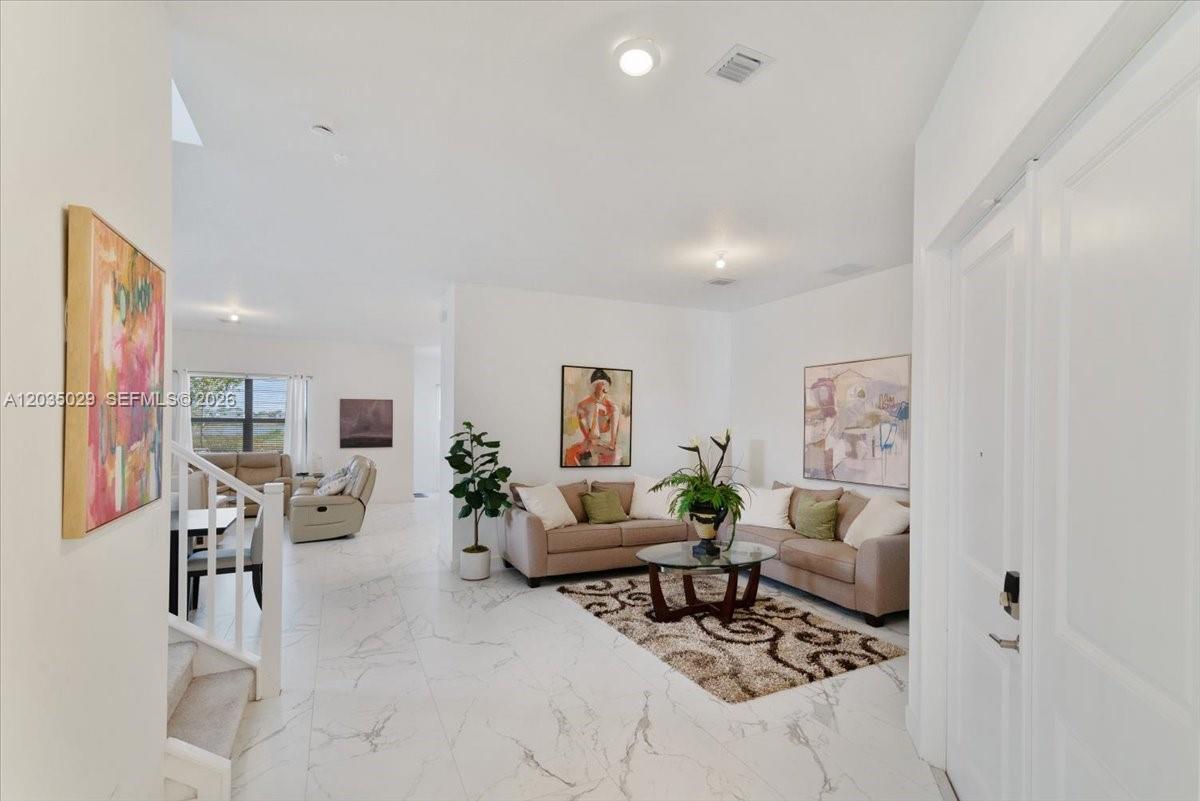 A bright living room features white marble floors, a beige sofa, and wall art — 17333 SW 46th St, Miramar FL 33029, MIRAMAR, FL