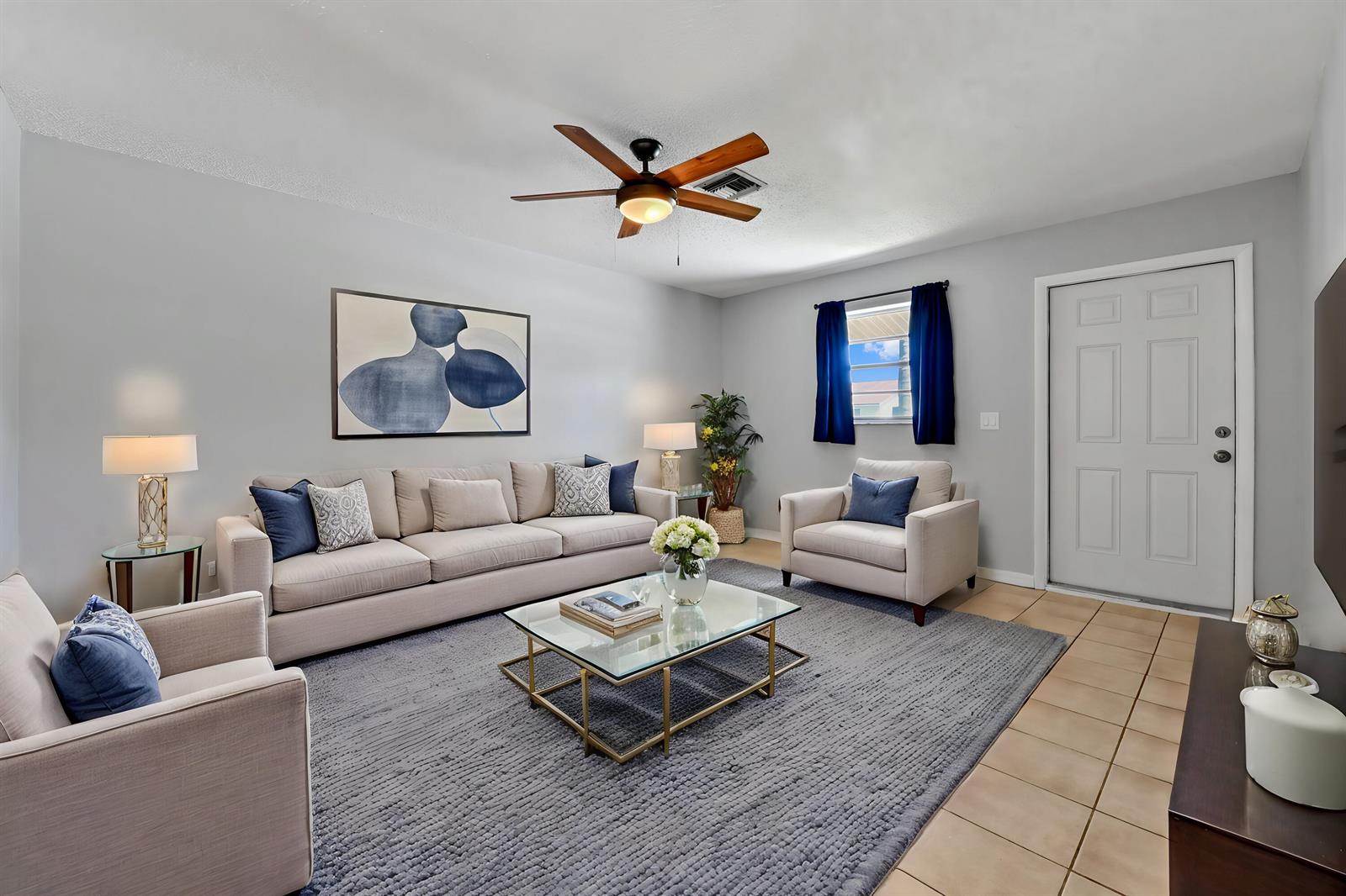 A living room features a beige sofa, two armchairs, a glass coffee table, and tile flooring — 4550 SE Salvatori Road, Stuart FL 34997, STUART, FL