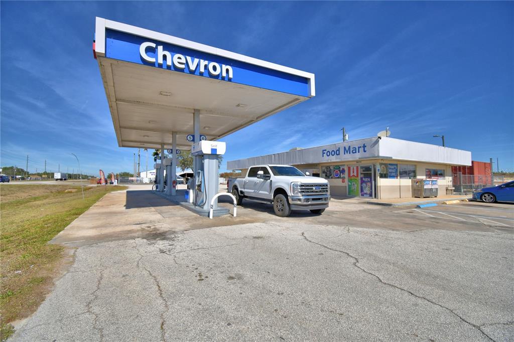 A white pickup truck is parked under a Chevron gas station canopy near a store — 16311 HWY 27, LAKE WALES, FL