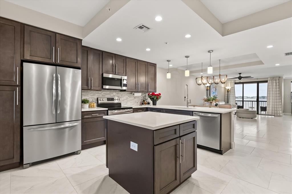 A modern kitchen features dark wood cabinets, stainless steel appliances, and a white quartz island — 16300 COUNTY ROAD 455 UNIT 204, MONTVERDE, FL
