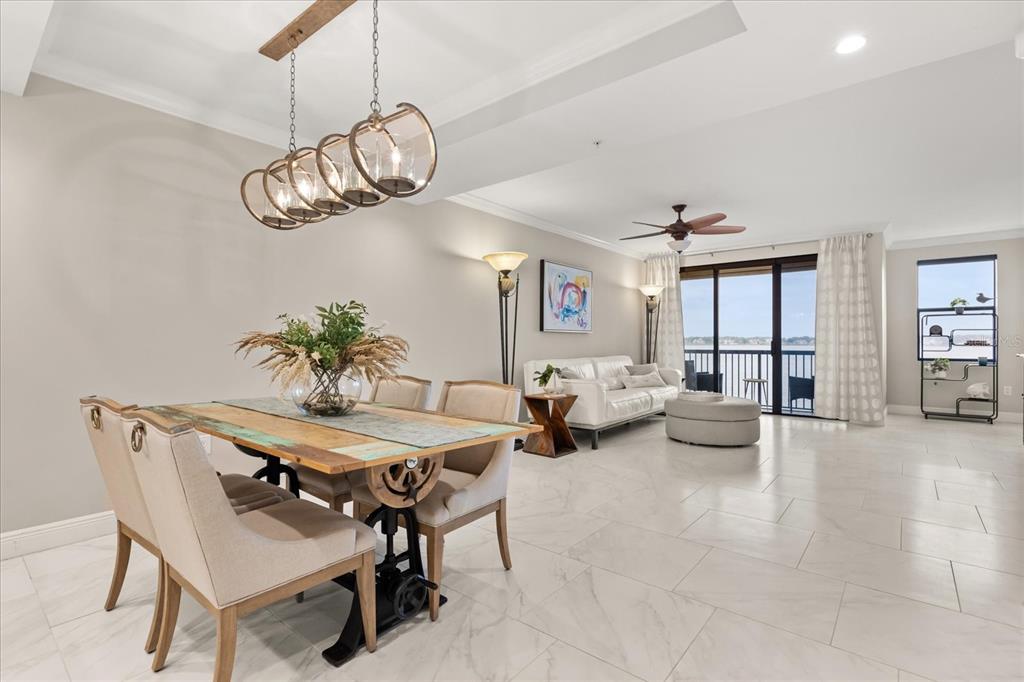 An open-concept dining and living area features tile floors, a rustic table, and balcony views — 16300 COUNTY ROAD 455 UNIT 204, MONTVERDE, FL