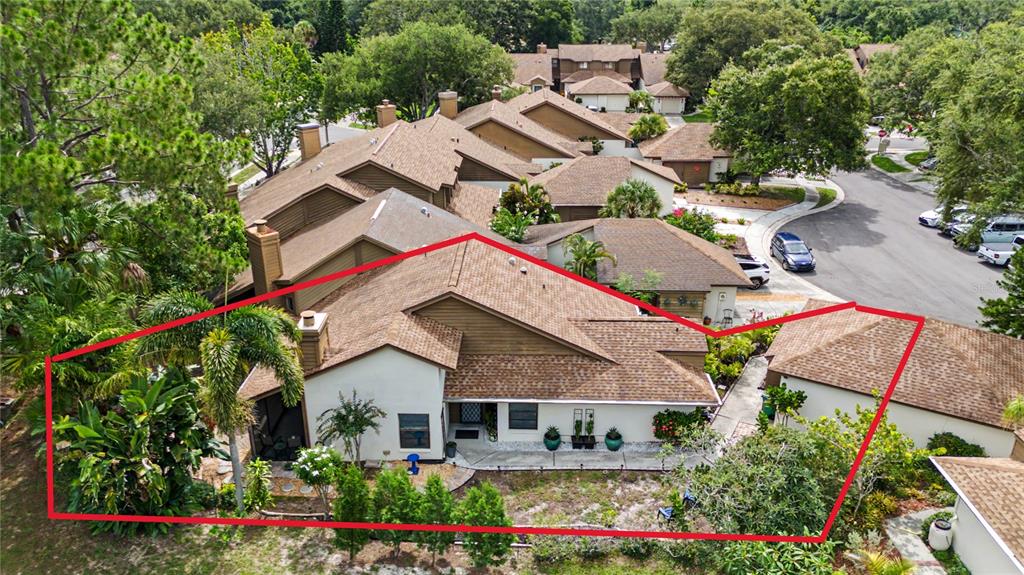 An aerial view shows the exterior of a multi-story townhouse with a brown shingled roof — 207 LIGHTHOUSE COURT, SAFETY HARBOR, FL