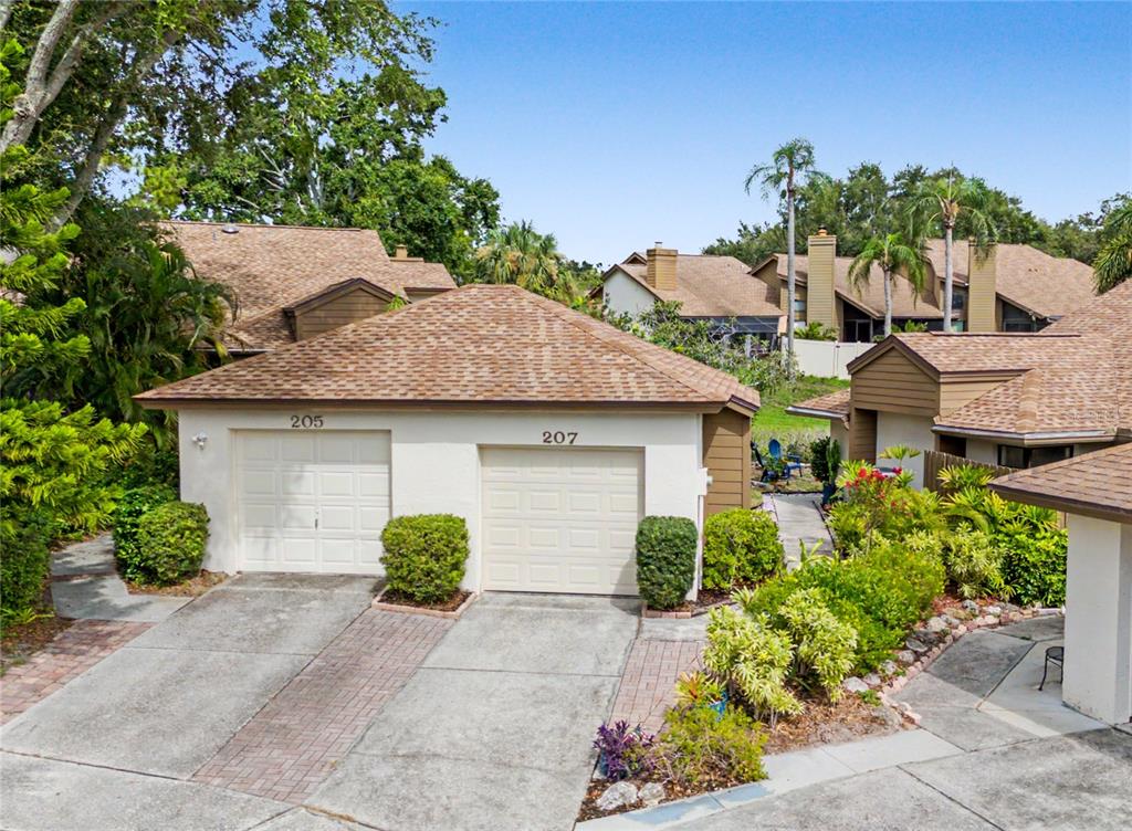 An exterior view of a duplex with two garage doors and a shared concrete driveway — 207 LIGHTHOUSE COURT, SAFETY HARBOR, FL