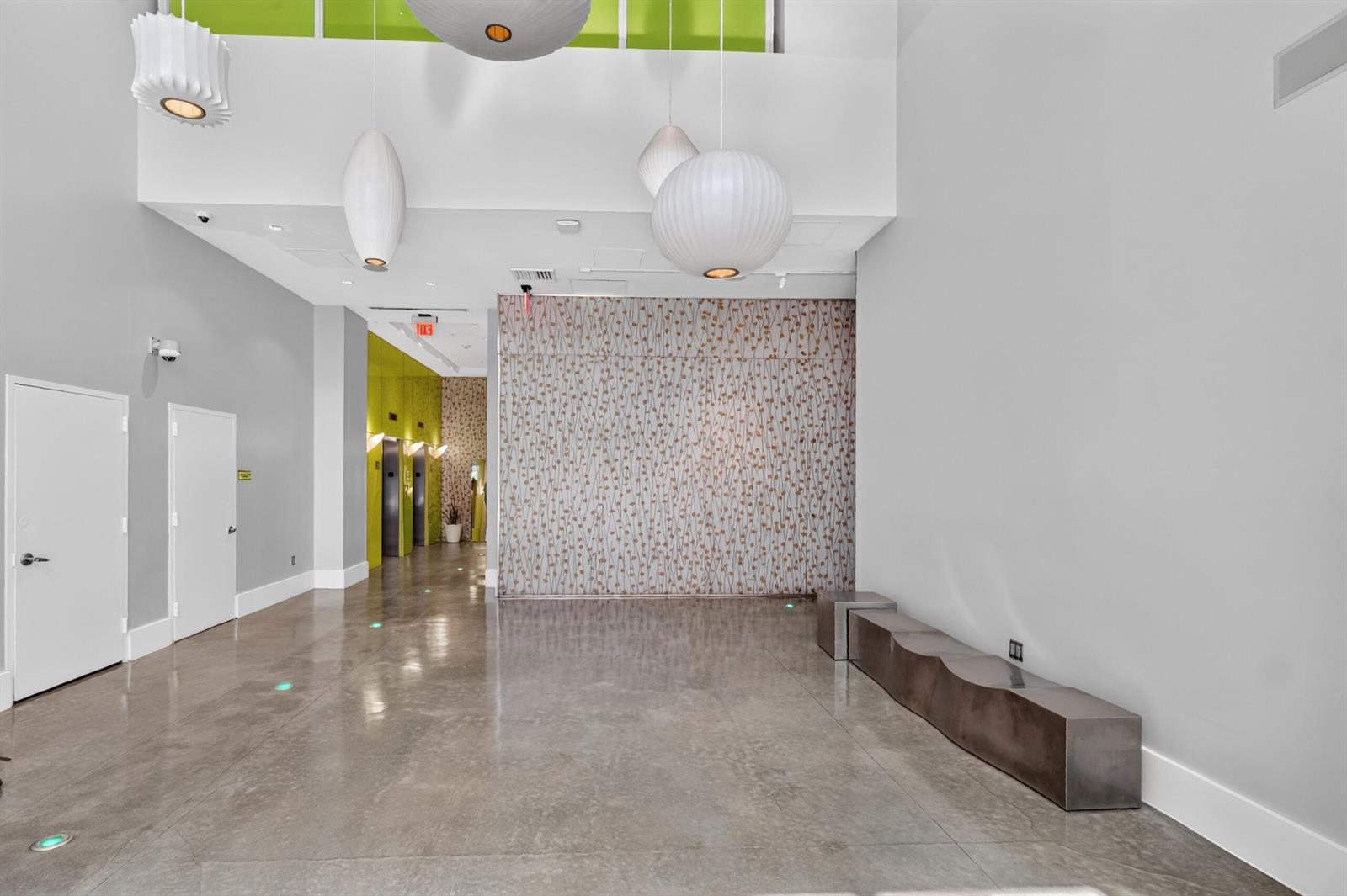 A modern lobby features polished concrete floors, a patterned accent wall, and several pendant lights — 133 NE 2nd Avenue # 1408, Miami FL 33132, MIAMI, FL