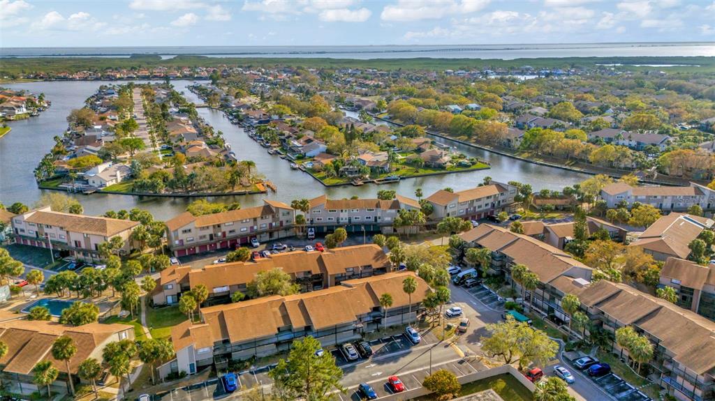An aerial view shows multi-story residential buildings surrounded by canals and lush green landscaping — 6320 NEWTOWN CIRCLE UNIT 20B1, TAMPA, FL