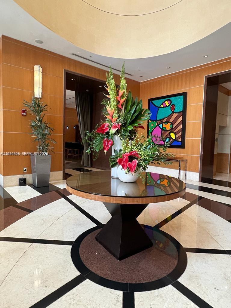 A circular table with a floral arrangement sits in a wood-paneled lobby with marble floors — 253 NE 2nd St # 3806, Miami FL 33132, MIAMI, FL
