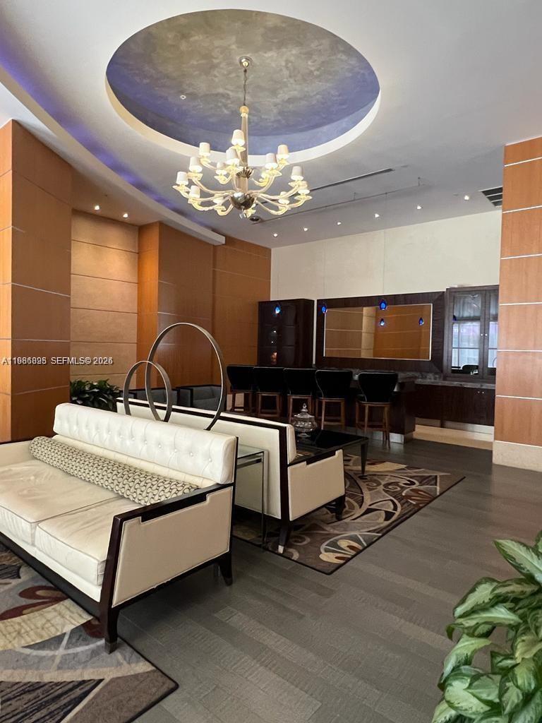A modern lounge area features white sofas, a chandelier, and a built-in bar — 253 NE 2nd St # 3806, Miami FL 33132, MIAMI, FL