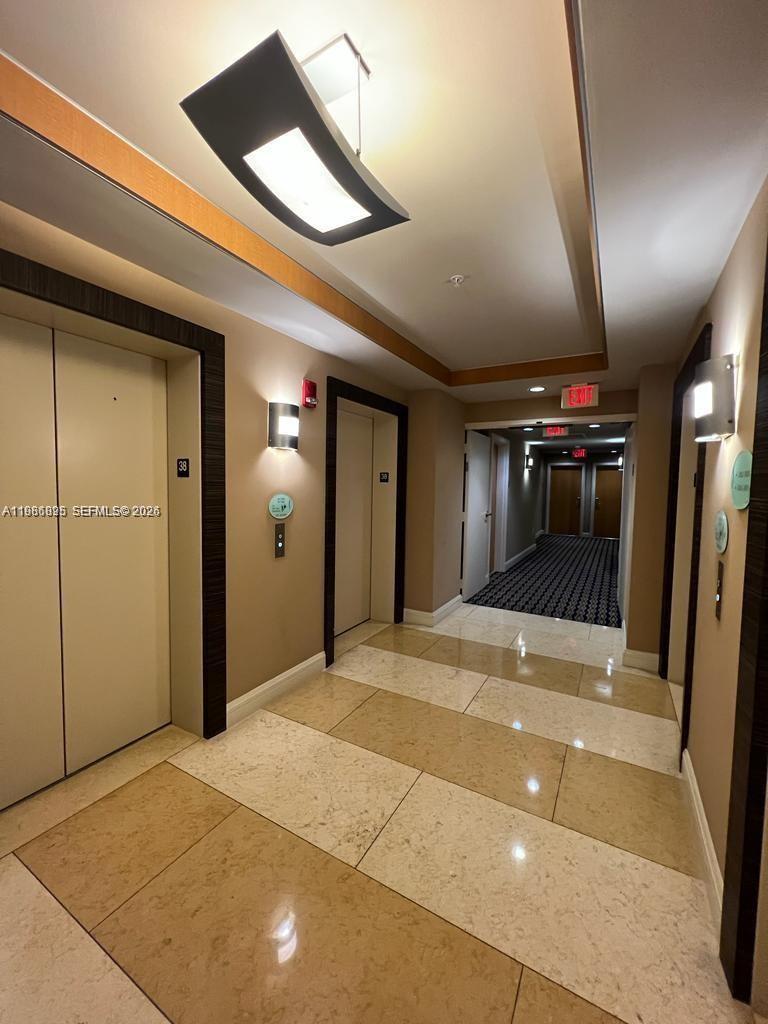 A brightly lit elevator lobby features beige tile flooring, two elevator doors, and a hallway — 253 NE 2nd St # 3806, Miami FL 33132, MIAMI, FL