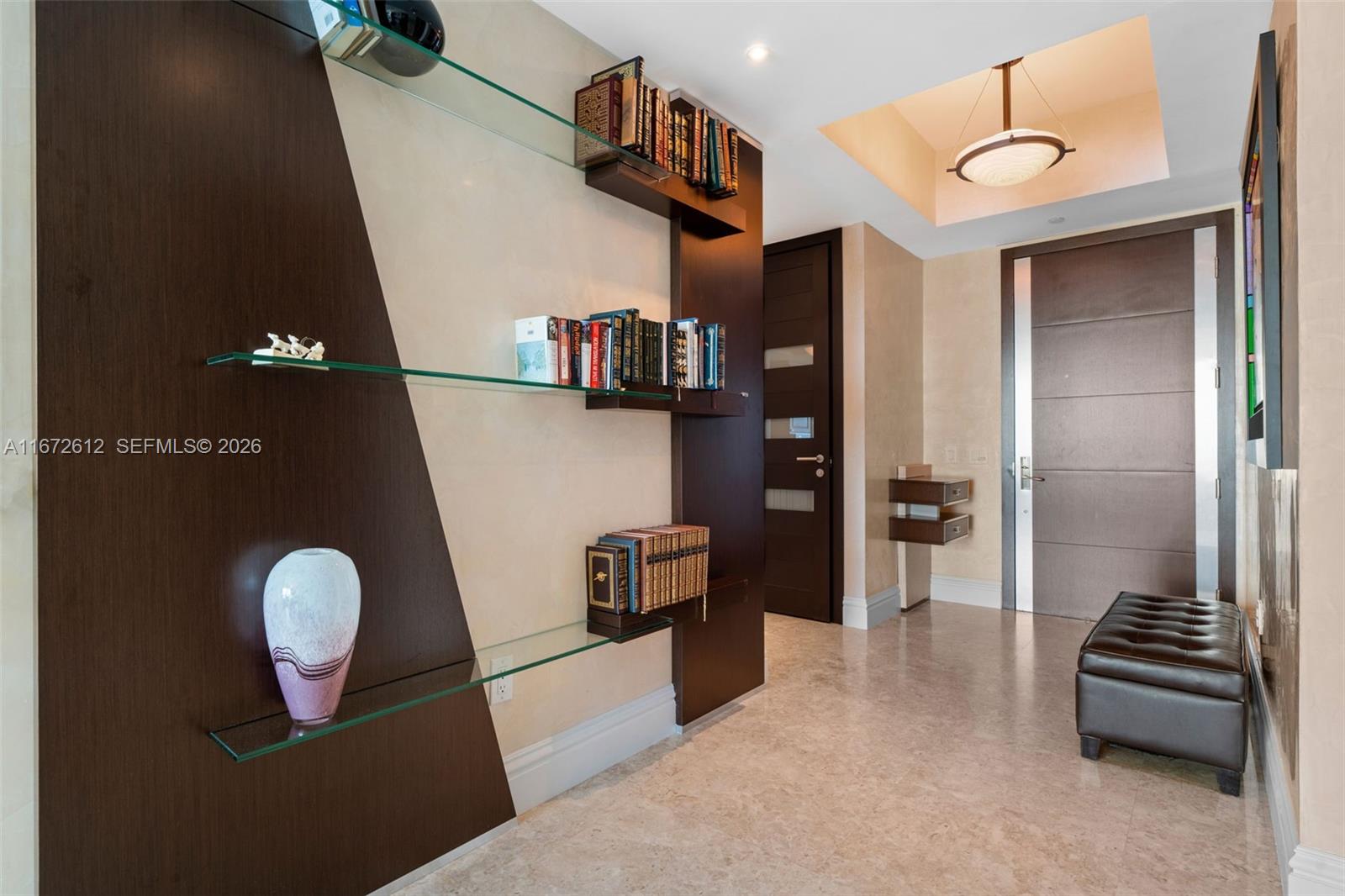 A modern hallway features glass shelving, dark wood accents, a leather bench, and marble flooring — 10295 Collins Ave # 1605, Bal Harbour FL 33154, BAL HARBOUR, FL