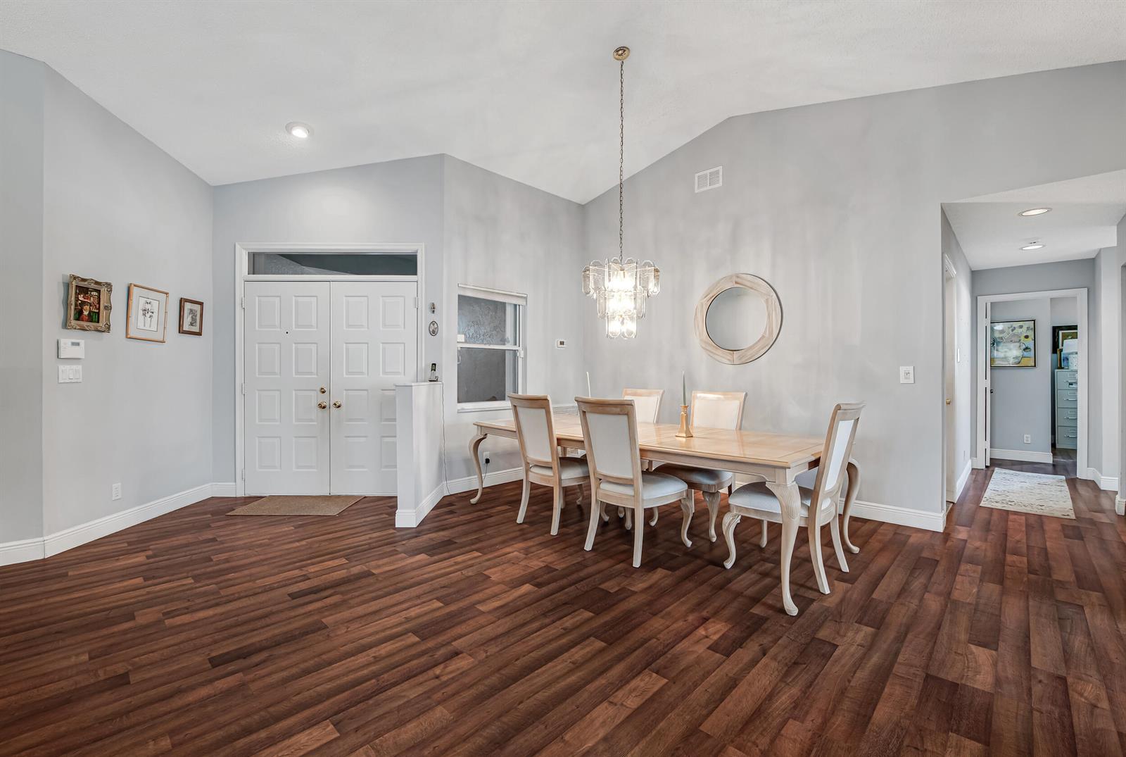 A dining room with a vaulted ceiling, wood flooring, and a chandelier over a wooden table — 9822 Harbour Lake Circle, Boynton Beach FL 33437, BOYNTON BEACH, FL