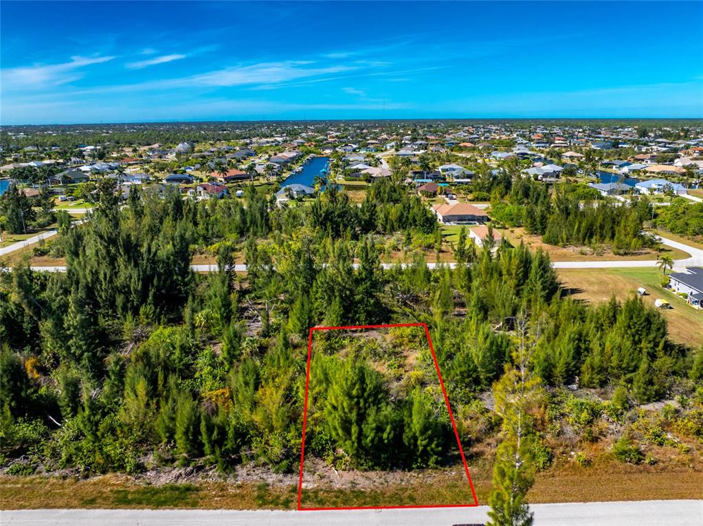An aerial view shows a vacant, wooded residential lot outlined in red along a road — 9259 LINGLE STREET, PORT CHARLOTTE, FL
