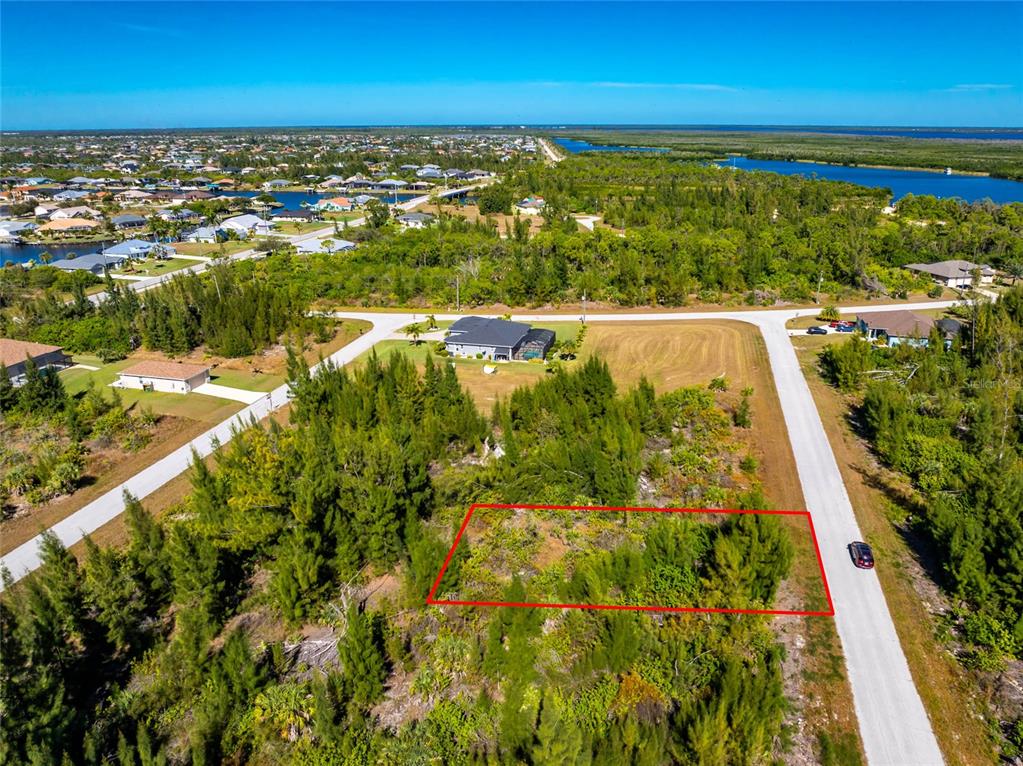 An aerial view shows a vacant, wooded residential lot outlined in red along a road — 9259 LINGLE STREET, PORT CHARLOTTE, FL
