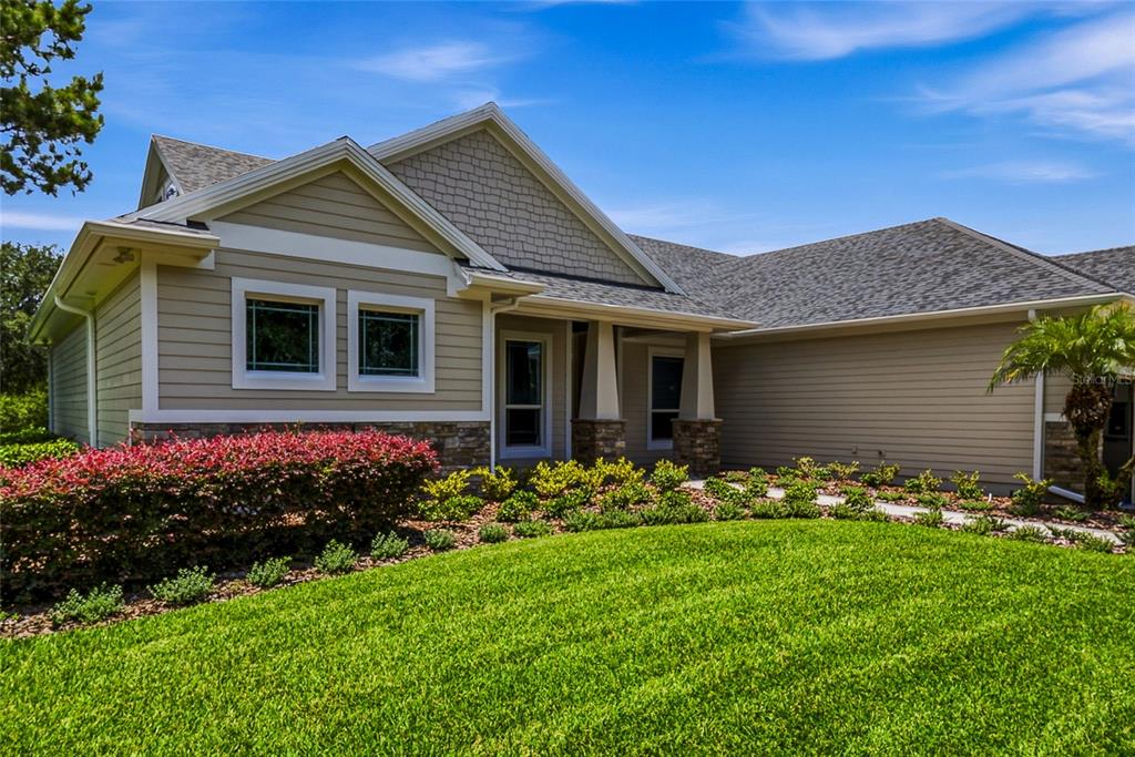 A single-story house with tan siding, stone accents, and a covered front porch — 2208 PRINCESS JULIA LANE, LUTZ, FL