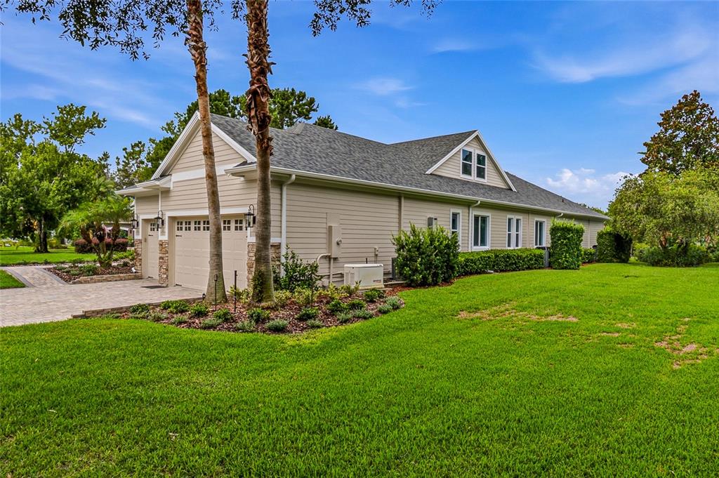 A side view of a beige house with a two-car garage and a grassy lawn — 2208 PRINCESS JULIA LANE, LUTZ, FL