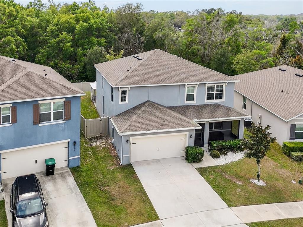 An aerial view shows two-story suburban houses with gray siding, shingled roofs, and concrete driveways — 3759 CRIMSON CLOVER DRIVE, MOUNT DORA, FL