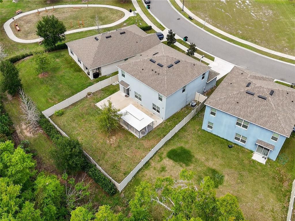 An aerial view shows three suburban houses with fenced backyards and a nearby walking path — 3759 CRIMSON CLOVER DRIVE, MOUNT DORA, FL