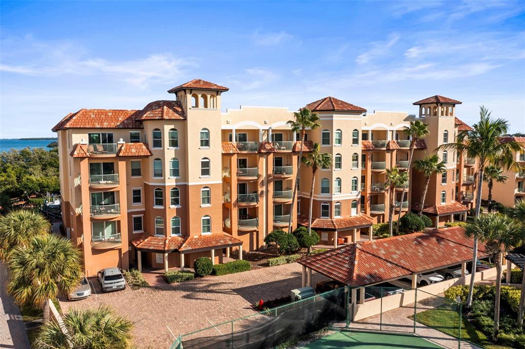 An exterior view of a multi-story Mediterranean-style apartment building with a tiled roof — 1645 PINELLAS BAYWAY S UNIT B2, TIERRA VERDE, FL