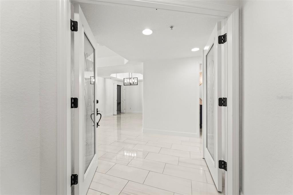 A bright entryway features white tile flooring and double glass-paneled doors opening into a hallway — 1645 PINELLAS BAYWAY S UNIT B2, TIERRA VERDE, FL