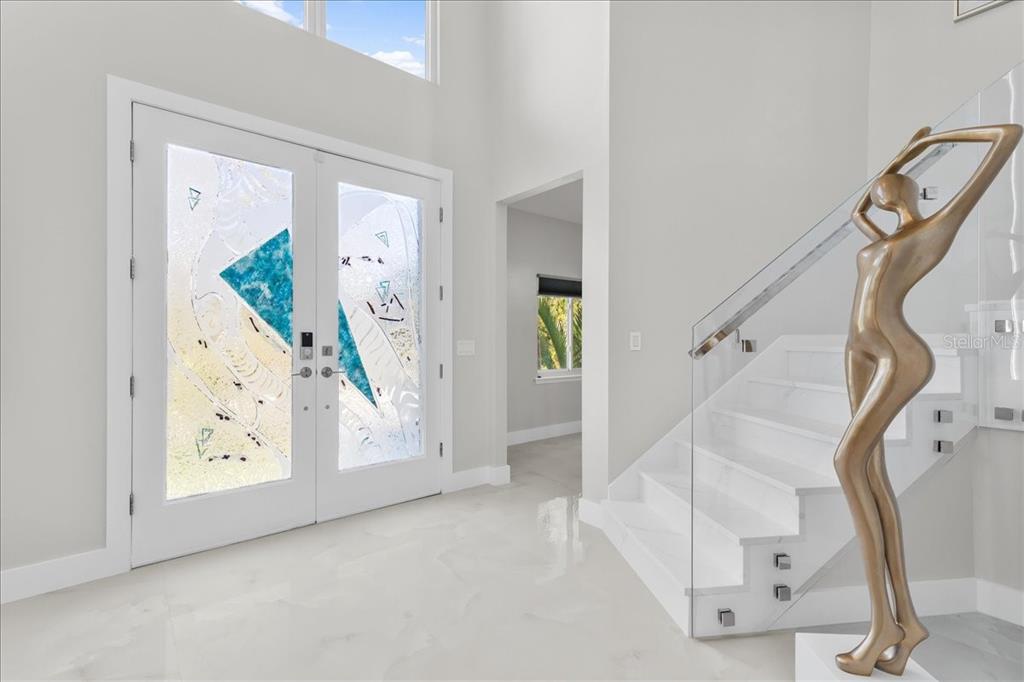 A bright entryway features white tile floors, double glass doors, and a modern staircase — 375 WELLINGTON AVENUE, OLDSMAR, FL