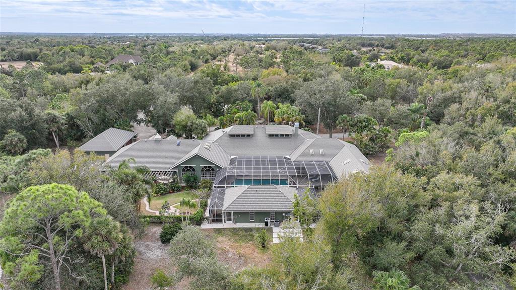 An aerial view shows a large house with a pool cage surrounded by dense trees — 24646 TANGERINE AVENUE, PORT CHARLOTTE, FL