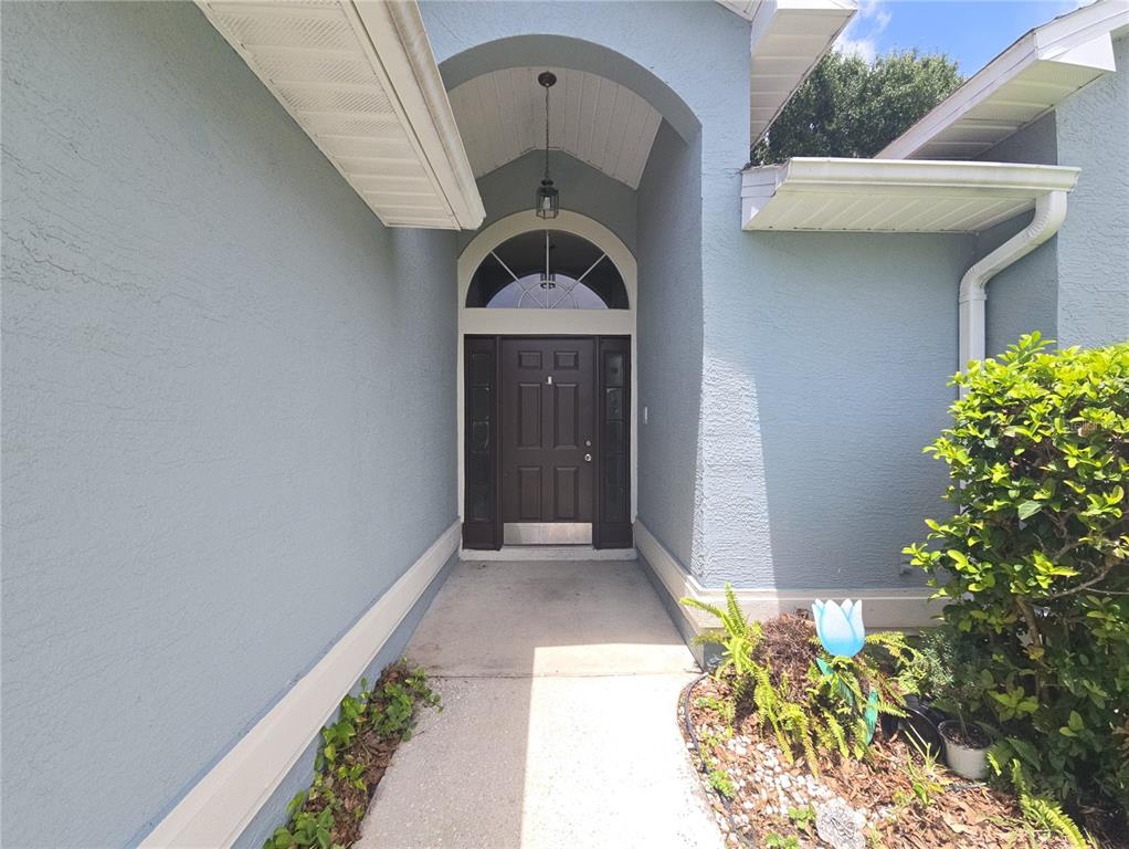 A blue stucco house exterior features a covered entryway with a dark brown front door — 3820 BLACKBERRY CIRCLE UNIT St Cloud, ST CLOUD, FL