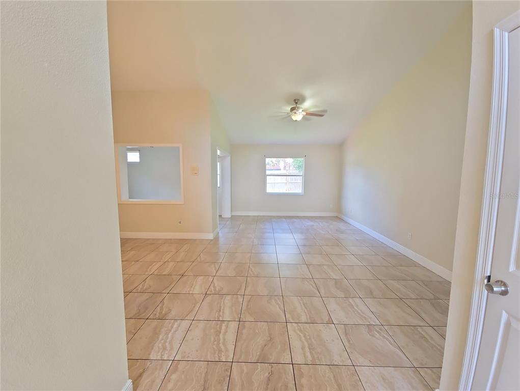 An empty room with vaulted ceilings, beige tile flooring, and a ceiling fan — 3820 BLACKBERRY CIRCLE UNIT St Cloud, ST CLOUD, FL