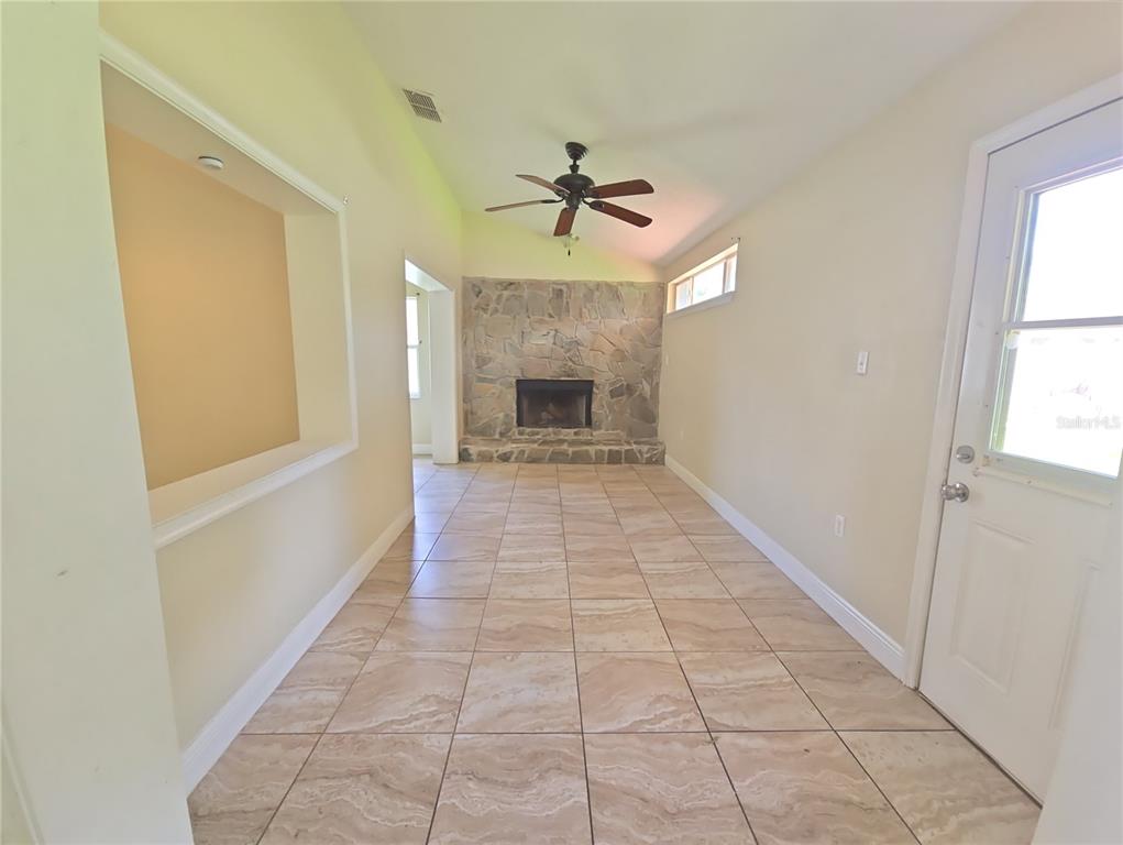 A room with tile flooring, a stone fireplace, and a ceiling fan — 3820 BLACKBERRY CIRCLE UNIT St Cloud, ST CLOUD, FL