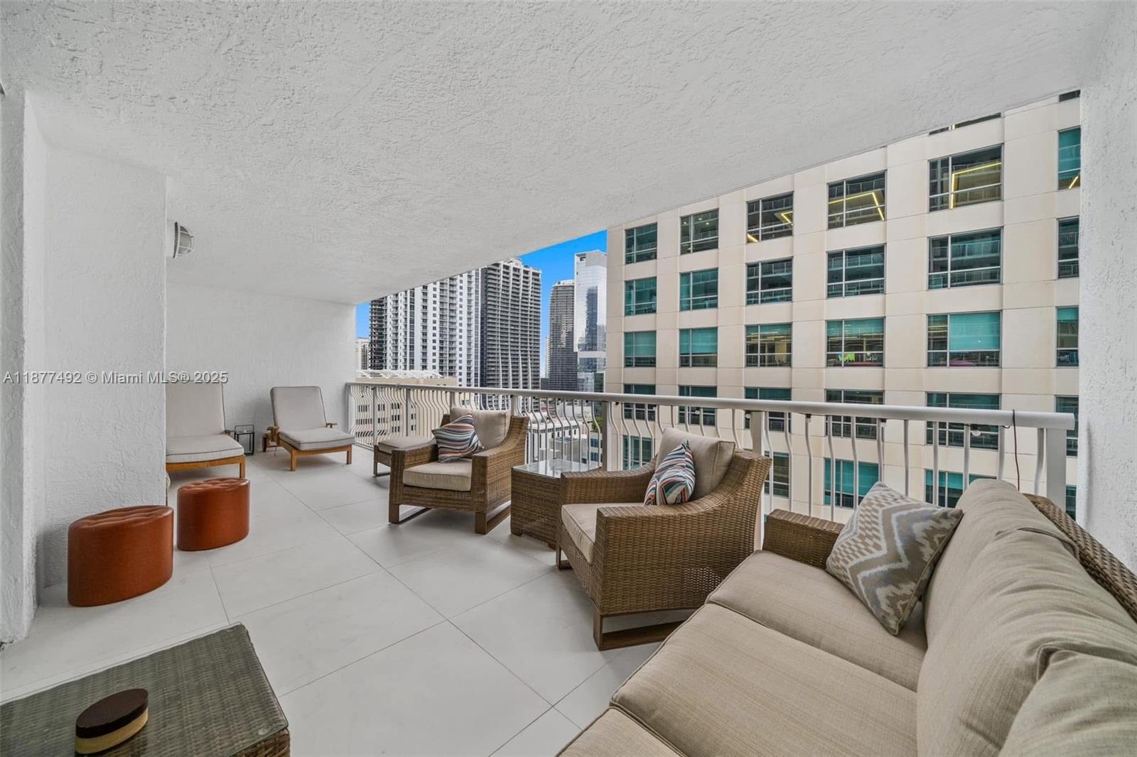A balcony features outdoor furniture, light-colored tile flooring, and views of surrounding city high-rises — 1200 Brickell Bay Dr # 2812, Miami FL 33131, MIAMI, FL
