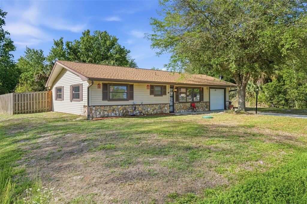 A single-story house with beige siding, stone accents, and a brown roof sits on grass — 6822 W DORIS MARETTA LANE, HOMOSASSA, FL