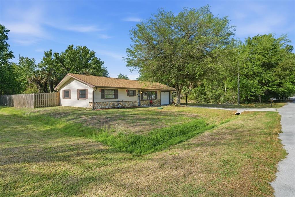 A single-story house with tan siding, stone accents, and a brown roof sits on grass — 6822 W DORIS MARETTA LANE, HOMOSASSA, FL