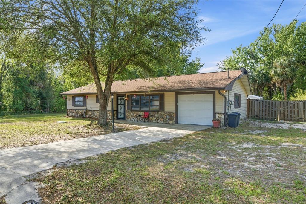 A single-story house with a stone facade, attached garage, and a large tree in front — 6822 W DORIS MARETTA LANE, HOMOSASSA, FL
