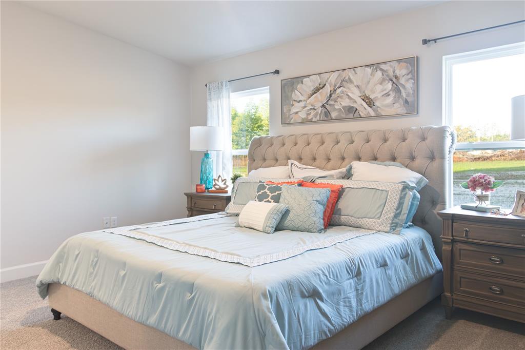 A bedroom features a tufted headboard, light blue bedding, two nightstands, and two windows — 3312 NE CAITLIN LANE, BELL, FL
