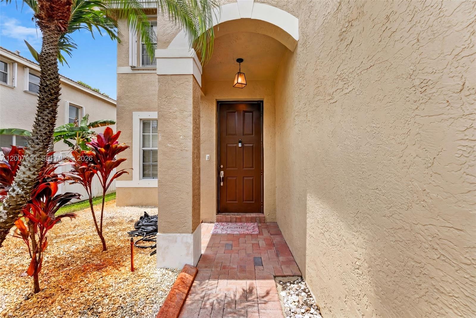 The exterior entrance features a brown front door, a brick walkway, and a palm tree — 16438 SW 28th St, Miramar FL 33027, MIRAMAR, FL