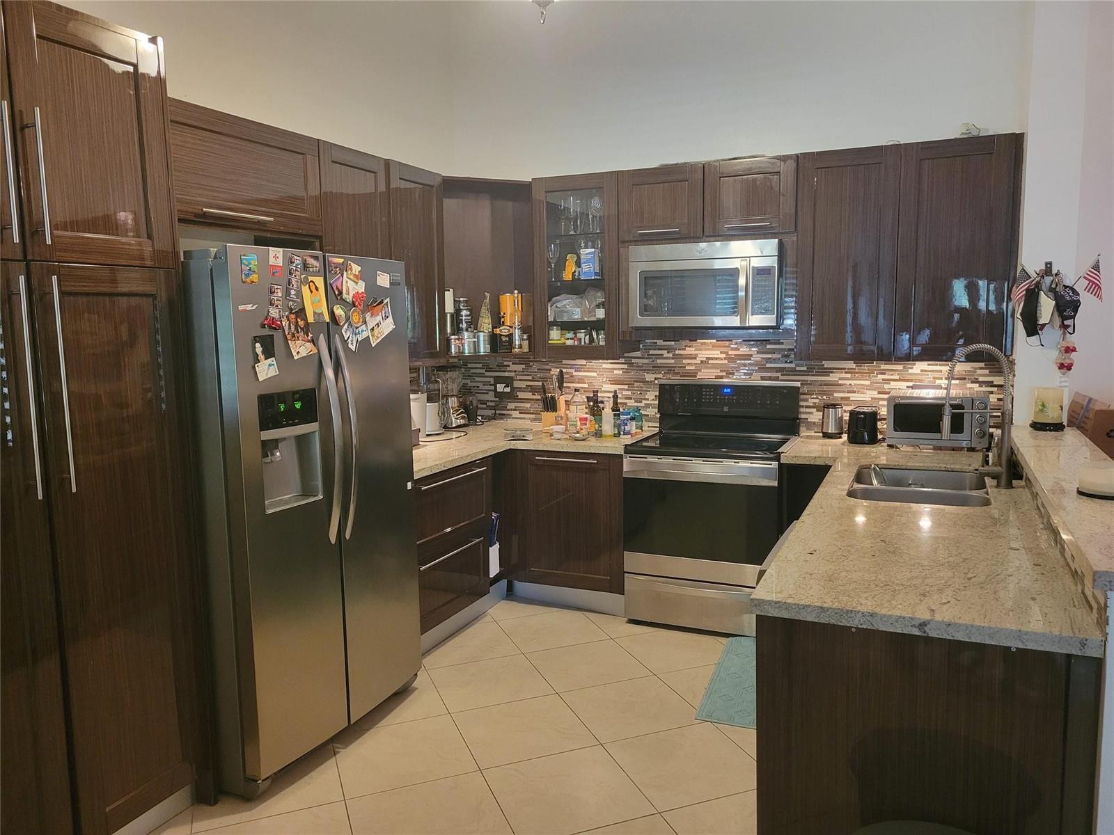 A kitchen features dark wood cabinets, stainless steel appliances, and light granite countertops — 13851 Oneida Drive # D2, Delray Beach FL 33446, DELRAY BEACH, FL