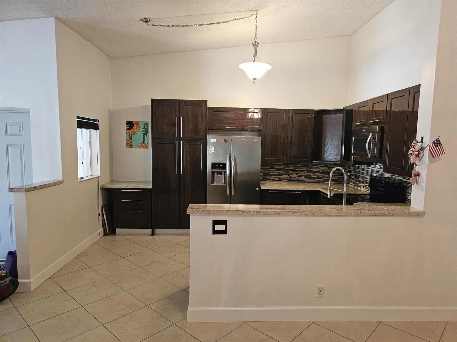 A kitchen features dark wood cabinets, stainless steel appliances, and a granite-topped breakfast bar — 13851 Oneida Drive # D2, Delray Beach FL 33446, DELRAY BEACH, FL