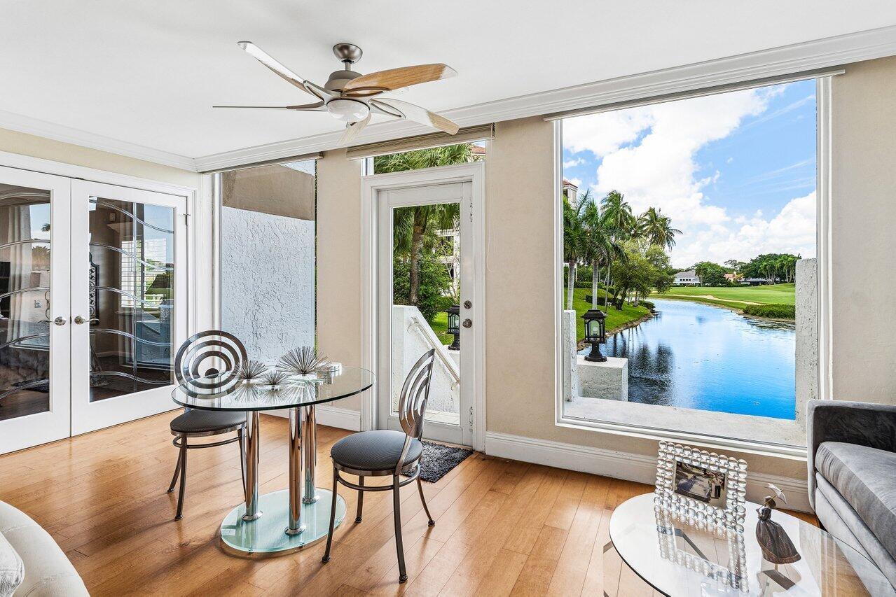 A sunroom features hardwood floors, a glass dining table, and large windows overlooking a lake — 7369 Orangewood Lane # 103, Boca Raton FL 33433, BOCA RATON, FL