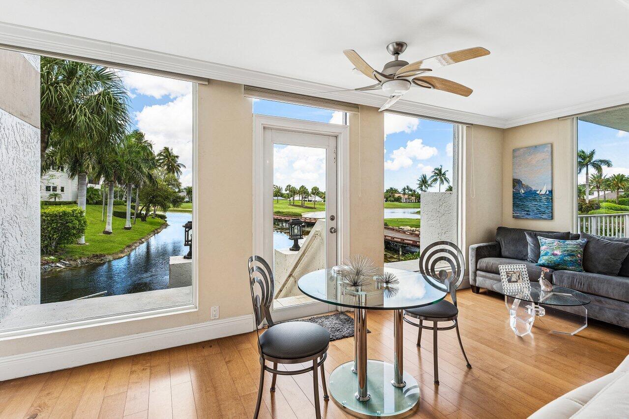 A sunroom with a glass dining table, sofa, hardwood floors, and views of a canal — 7369 Orangewood Lane # 103, Boca Raton FL 33433, BOCA RATON, FL