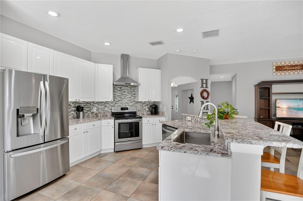 A kitchen with white cabinets, stainless steel appliances, granite countertops, and tile flooring — 2675 RUNNING SPRINGS LOOP, OVIEDO, FL