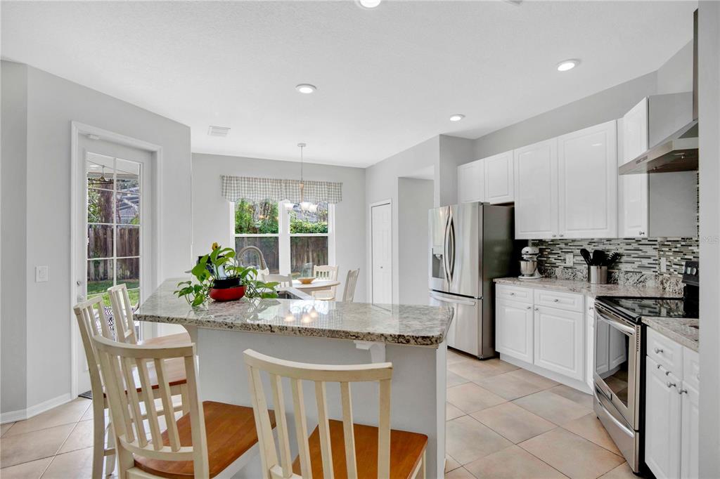 A kitchen features white cabinets, granite countertops, stainless steel appliances, and an attached breakfast bar — 2675 RUNNING SPRINGS LOOP, OVIEDO, FL