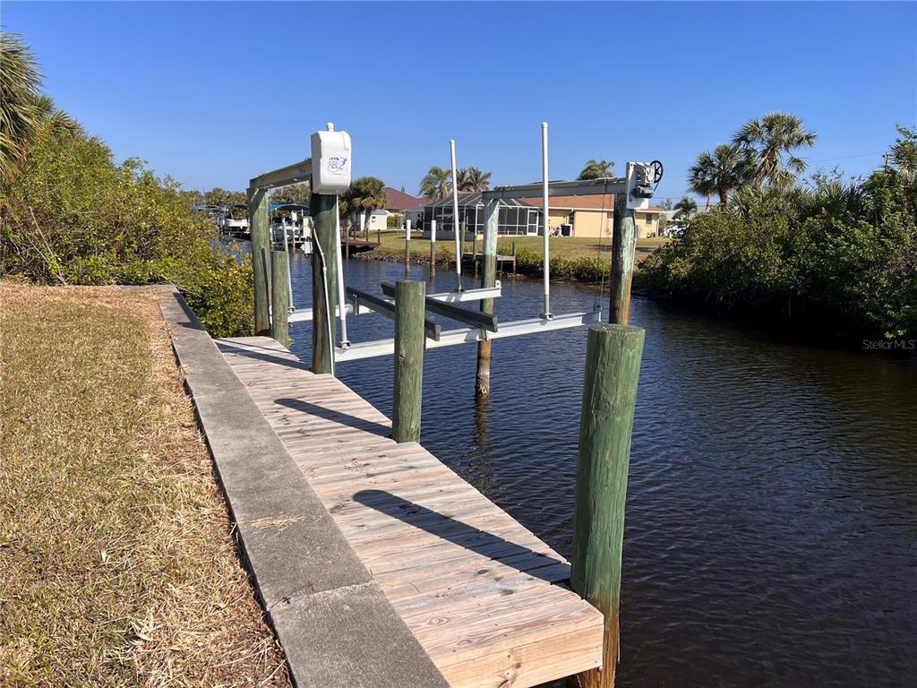 A wooden dock with a boat lift extends into a narrow canal — 4466 BAYVIEW STREET, PORT CHARLOTTE, FL
