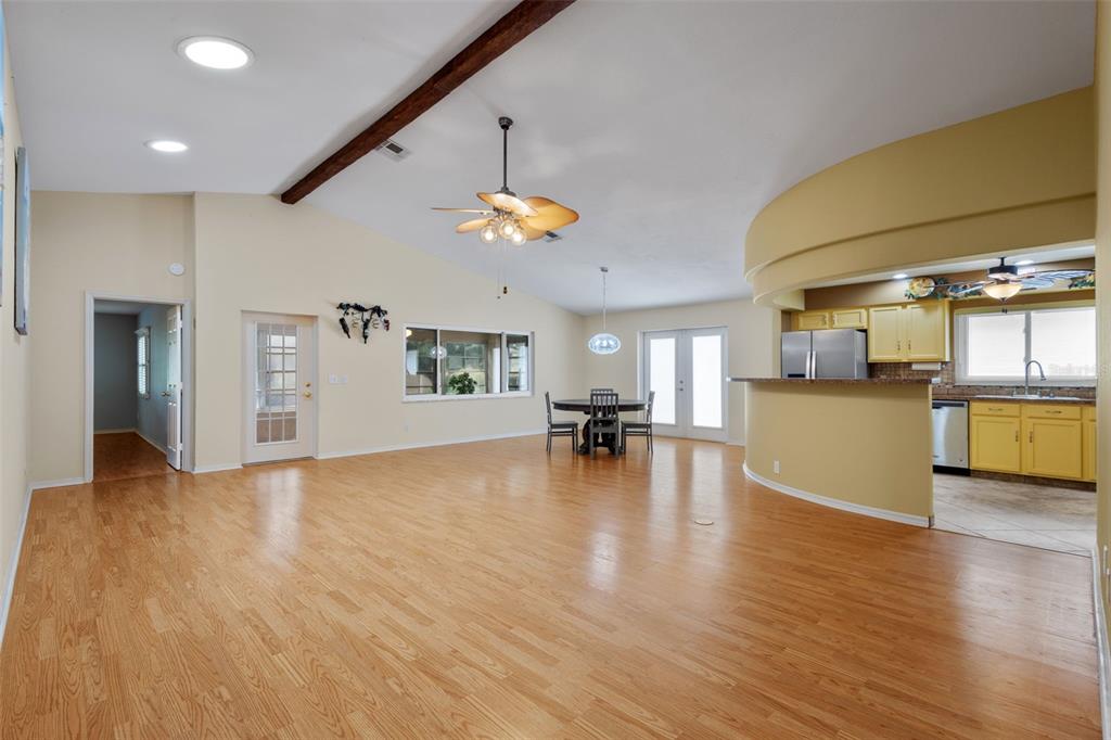 A spacious living and dining area with hardwood floors, a vaulted ceiling, and an open kitchen — 9526 SW 92ND PLACE ROAD, OCALA, FL