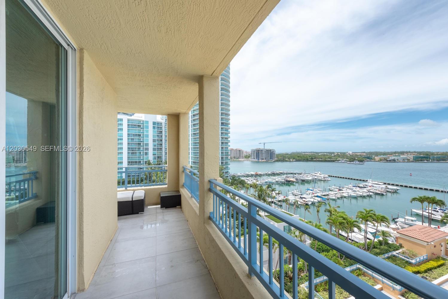 A balcony with a blue railing overlooks a marina and high-rise buildings — 90 Alton Rd # 1102, Miami Beach FL 33139, MIAMI BEACH, FL