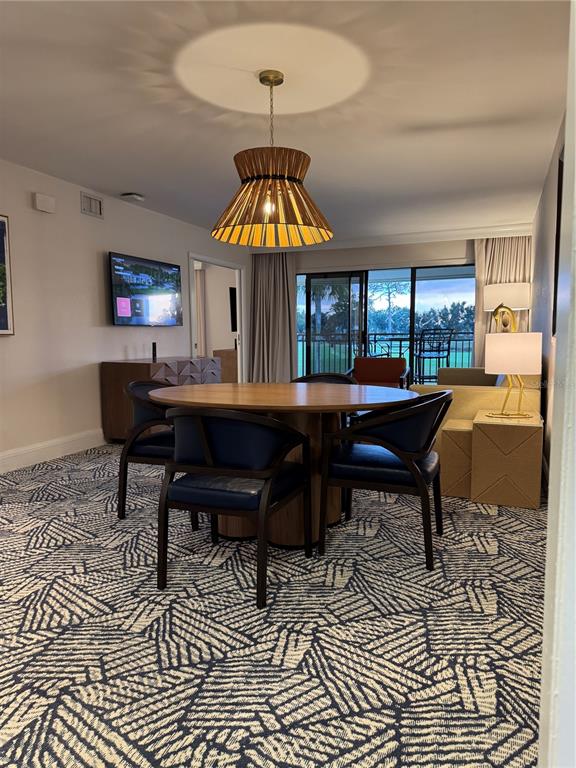 A dining area features a round wooden table, dark chairs, and a patterned carpet — 4782 FOX HUNT DRIVE UNIT D654, WESLEY CHAPEL, FL