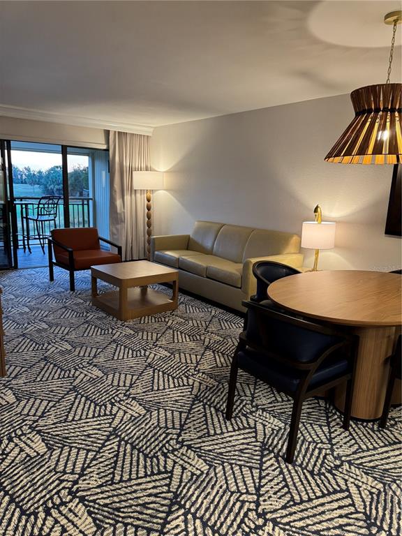 A living and dining area features patterned carpet, a sofa, armchairs, and a balcony view — 4782 FOX HUNT DRIVE UNIT D654, WESLEY CHAPEL, FL