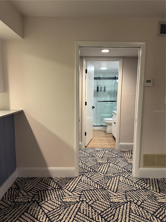 A doorway leads from a carpeted room into a bathroom with a glass-enclosed shower — 4782 FOX HUNT DRIVE UNIT D654, WESLEY CHAPEL, FL